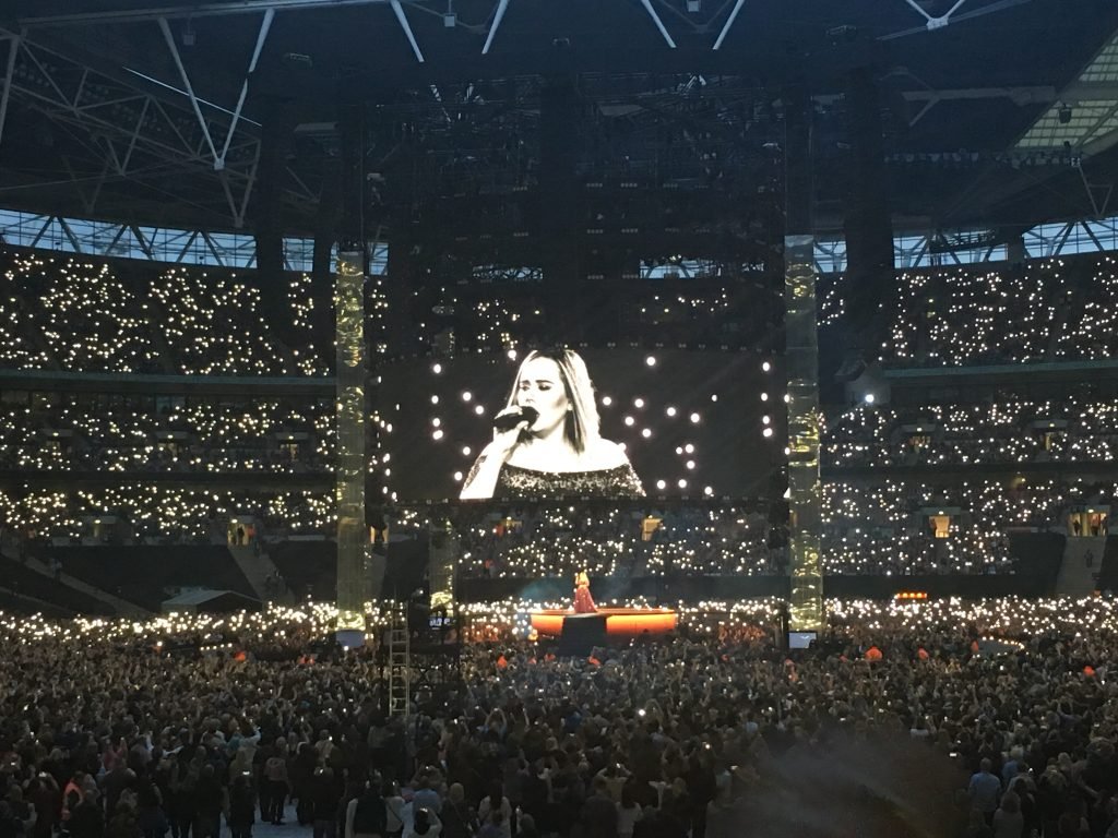 Una cantante realiza presentación ante una multitud y su imagen es proyectada en pantallas LED P5 exterior gigante en evento masivo iluminado con luces LED